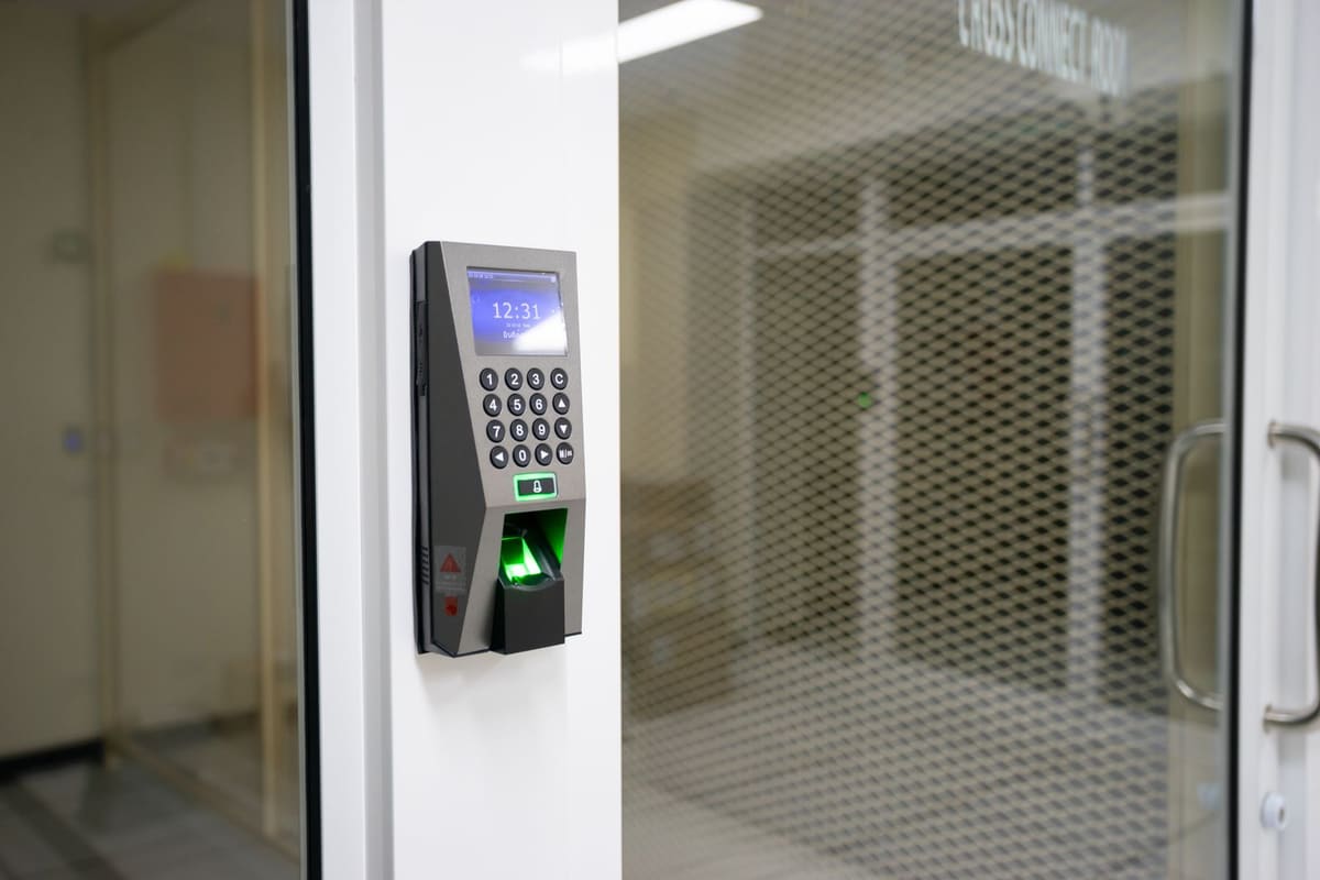 A fingerprint access control reader beside a secure glass door